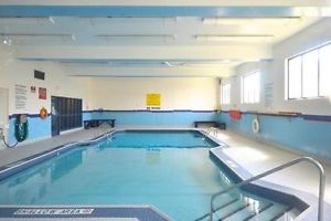 A picture of the indoor community pool from the shallow-end looking towards the deep-end.